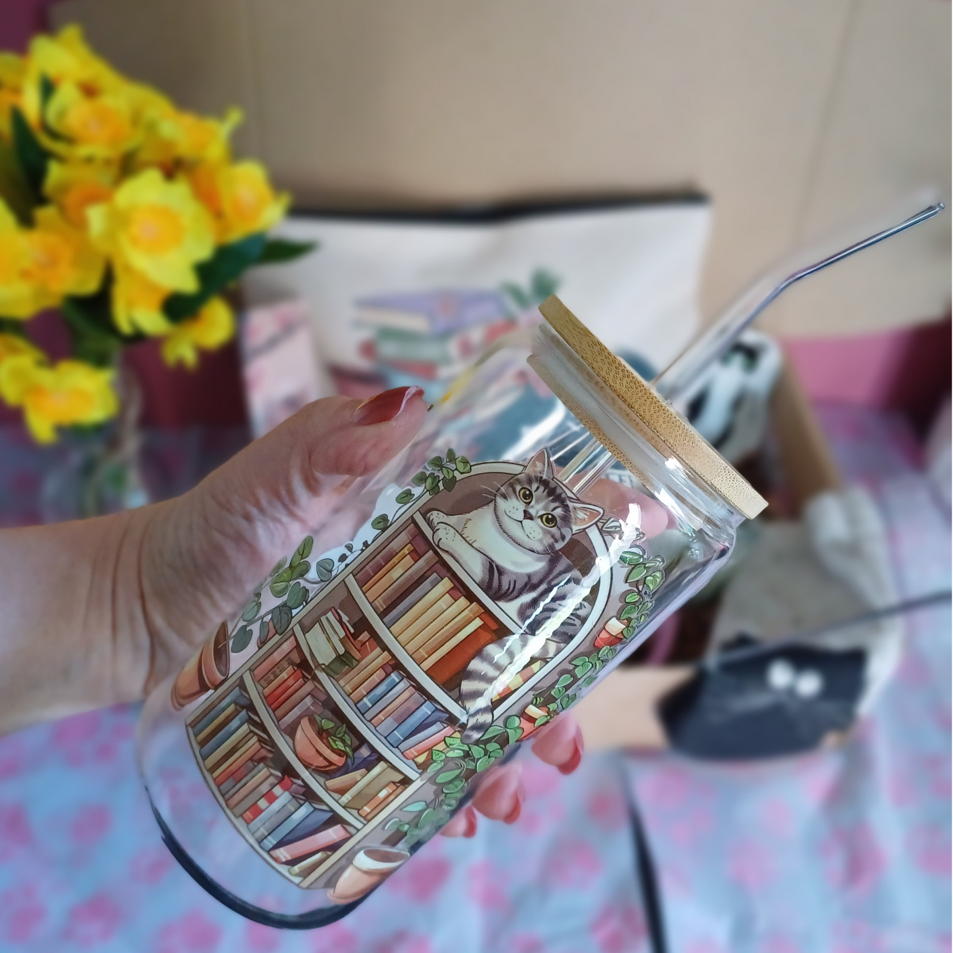 Glass tumbler featuring a cat sitting on a bookshelf with butterflies around.
